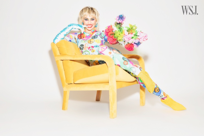 Sporting peace signs, Miley Cyrus poses with a flower bouquet.