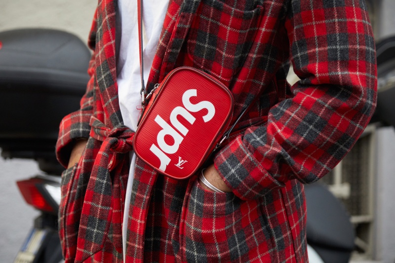 Man wearing red Supreme Louis Vuitton bag.