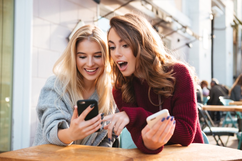 Young Women Checking Phones Interested