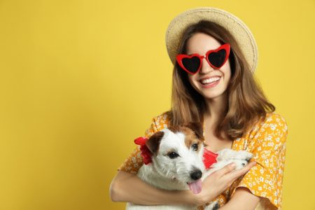 Is It Safe to Give CBD Oil to Pets? Smiling Woman Heart Sunglasses Hat Holding Jack Russell Terrier Dog