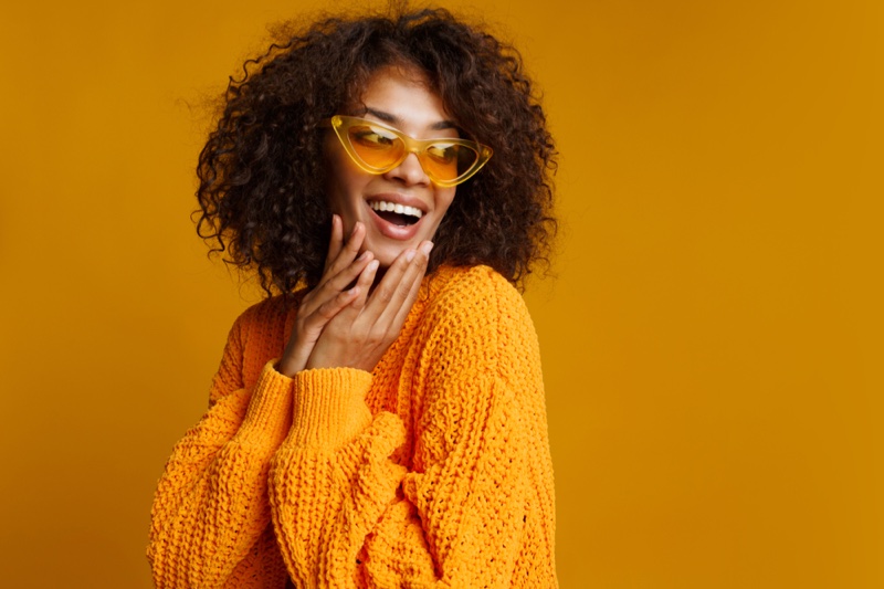 Smiling Black Woman Curly Hair Yellow Sweater Cat-Eye Sunglasses