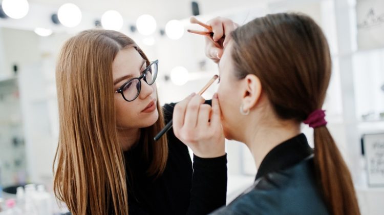 The Benefits of a Career in Beauty Attractive Makeup Artist Wearing Glasses Applying Makeup on Model