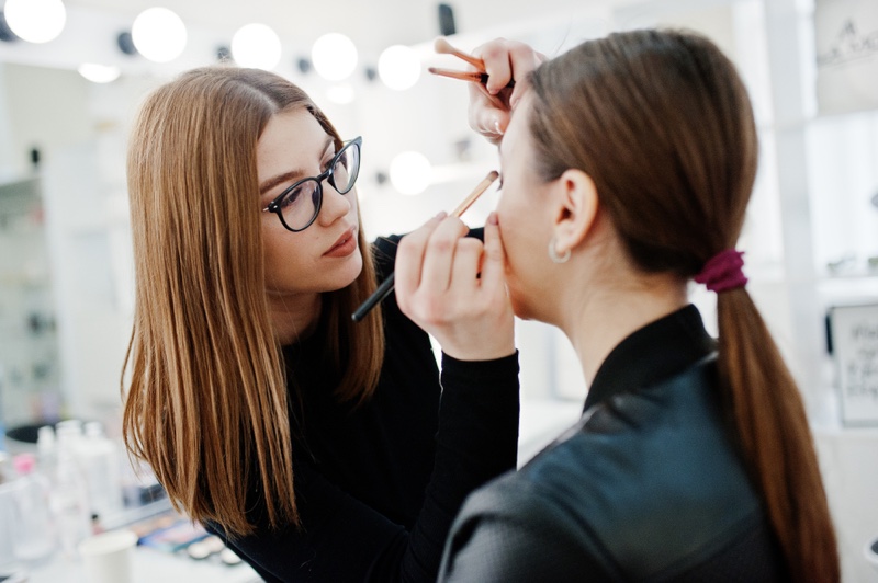 Attractive Makeup Artist Wearing Glasses Applying Makeup on Model