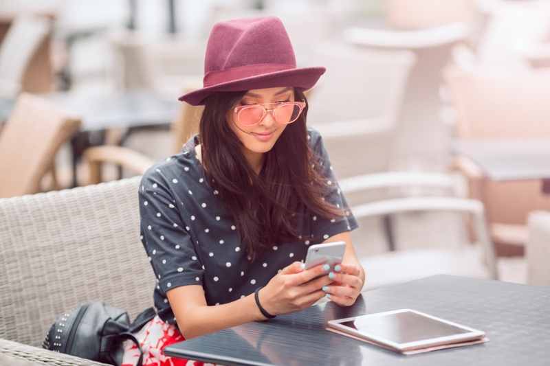 Fashionable Woman Looking Phone Tablet Hat Sunglasses Polka Dot Shirt