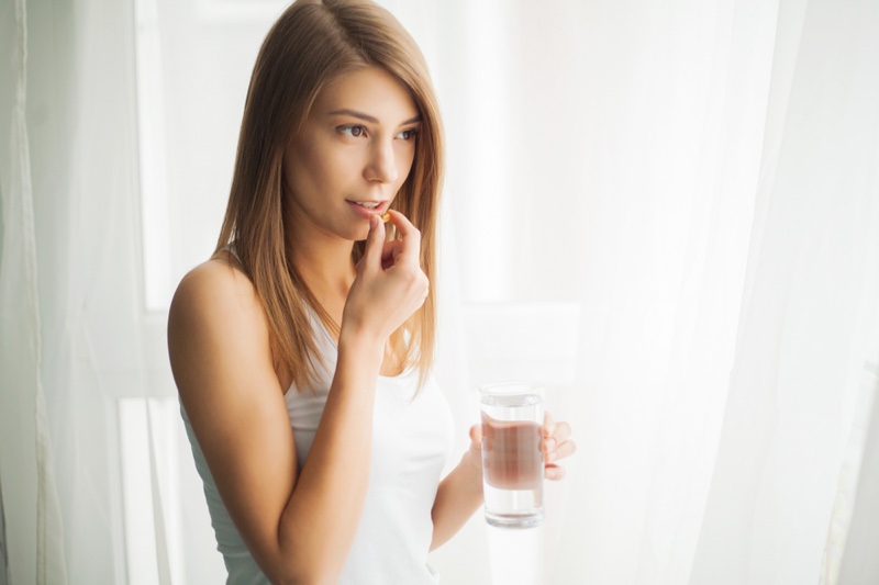 Woman Taking Pill Vitamin Supplement Holding Water Glass