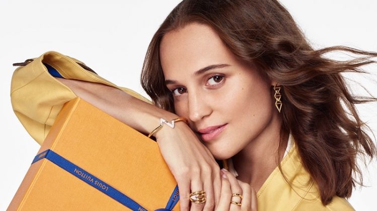Alicia Vikander poses with an oversized Louis Vuitton gift box for the brand's holiday 2020 campaign. The actress charms in a yellow Louis Vuitton coat, complete with leather monogram detailing.