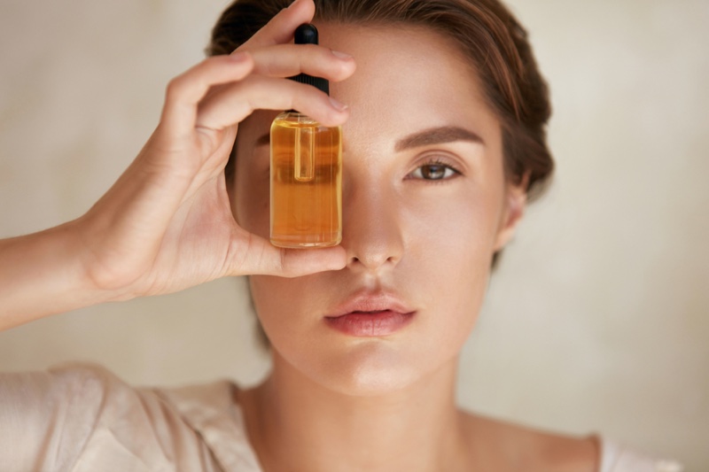 Beauty Model Oil Bottle Holding Closeup Face