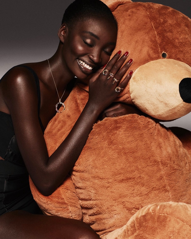 Posing with a large teddy bear, Diarra Ndiaye models Dolce & Gabbana Alphabet jewelry collection.