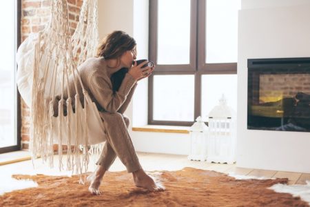 This Winter, Make Your Place Look Elegant and Effortlessly Warm Woman Drinking Electric Fireplace Seat