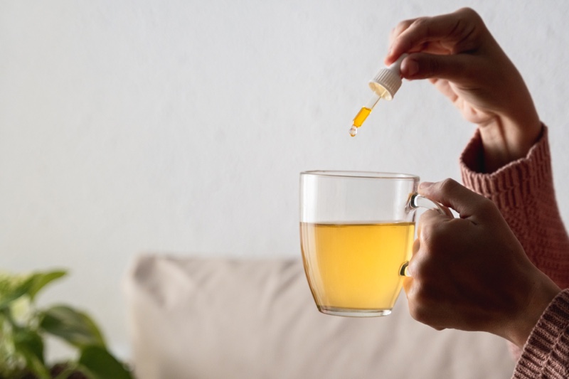 Woman Adding CBD Oil Tea Cup