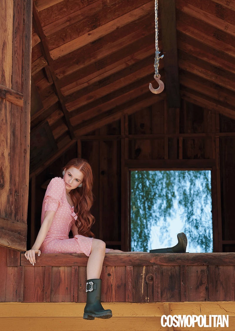Chilling in a barn, Madelaine Petsch wears Alessandra Rich dress, Roger Vivier boots, and Sauer earrings.
