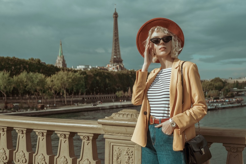 woman yellow jacket striped t shirt brown belt jeans hat