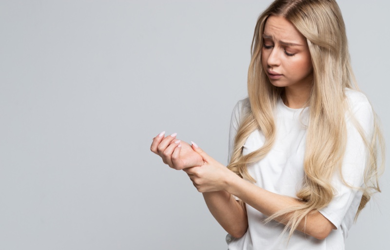 Blonde Woman Long Hair Holding Wrist Injury Chronic Pain