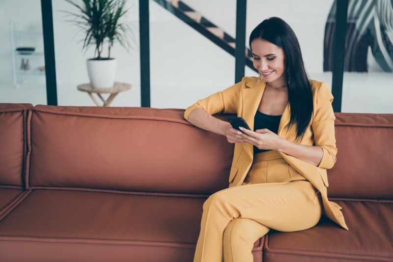 Woman Wearing Yellow Pant Suit Sitting Couch Looking Phone