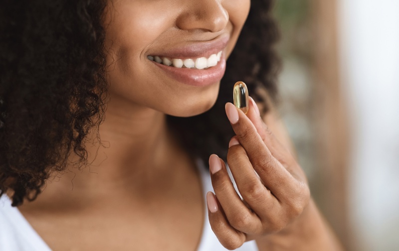 Black Woman Taking Vitamin Smiling Teeth