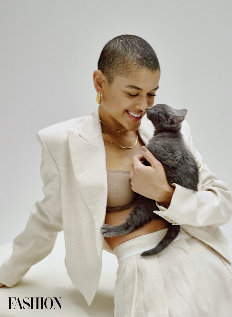 Holding a cat, Jordan Alexander poses in stylish outfit.