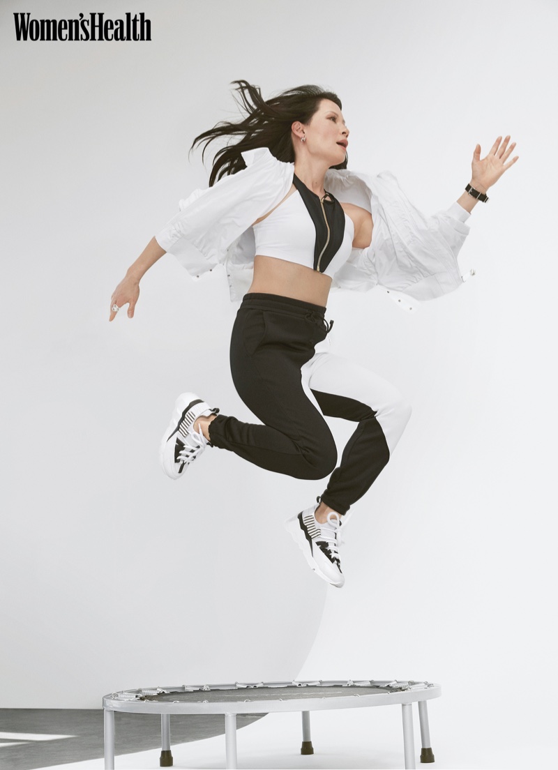 Lucy Liu takes a leap in Athleta jacket, Oye Swimwear top, Koral pants, and Pierre Hardy sneakers.