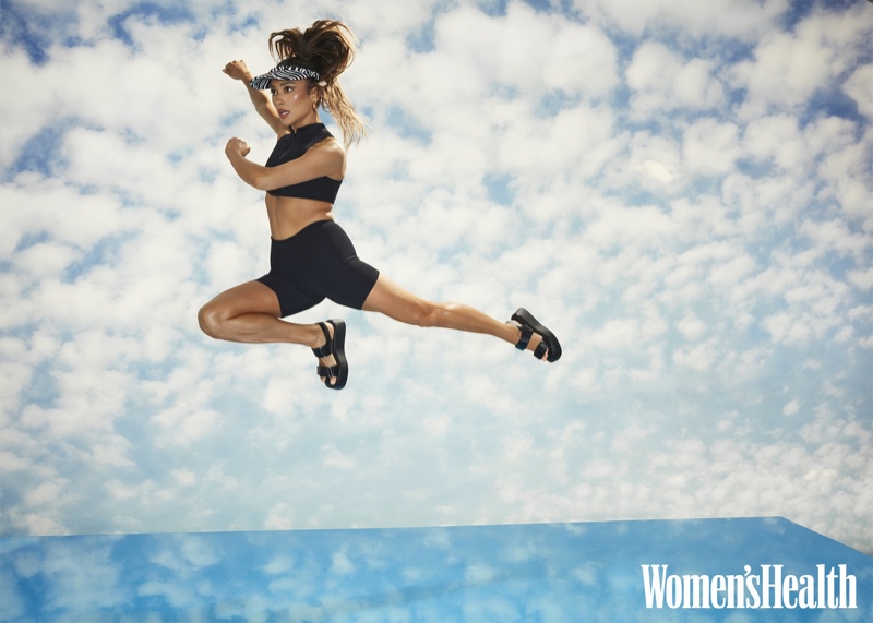 Taking a leap, Shay Mitchell wears Bondeye top and shorts, Lele Sadoughi x Solid & Striped visor, and Vagabond Shoemakers sandals.