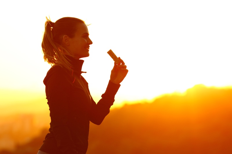 Smiling Woman Holding Protein Bar Outdoors Sun