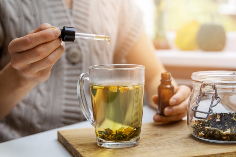 Woman Adding CBD Oil Tea