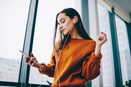 Fun Ideas to Try When You’re at Home (2021) Woman Listening Music Podcast Earphones Orange Sweater