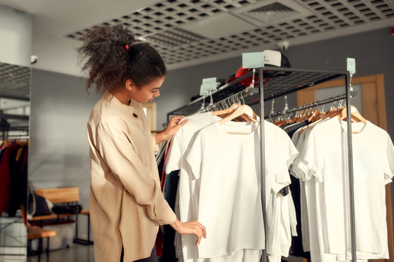 Woman Selecting T-Shirts Hanging Rack