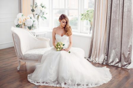 Bride Sitting Long Wedding Dress Strapless Holding Flowers