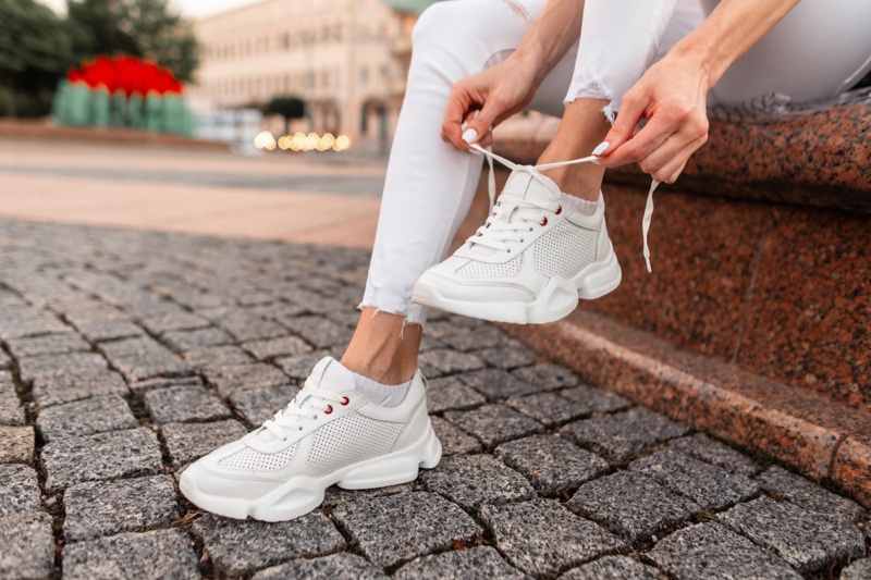 Woman Lacing Up White Sneakers