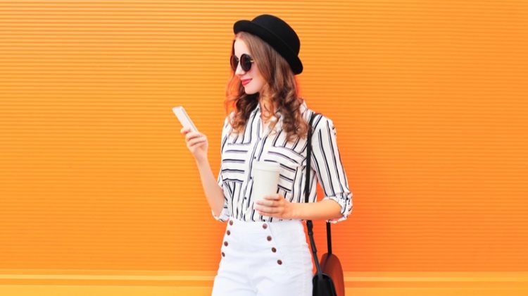 Woman Striped Blouse White Pants Holding Phone Cup