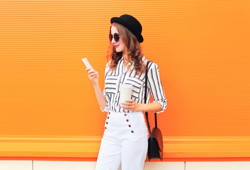 Woman Striped Blouse White Pants Holding Phone Cup