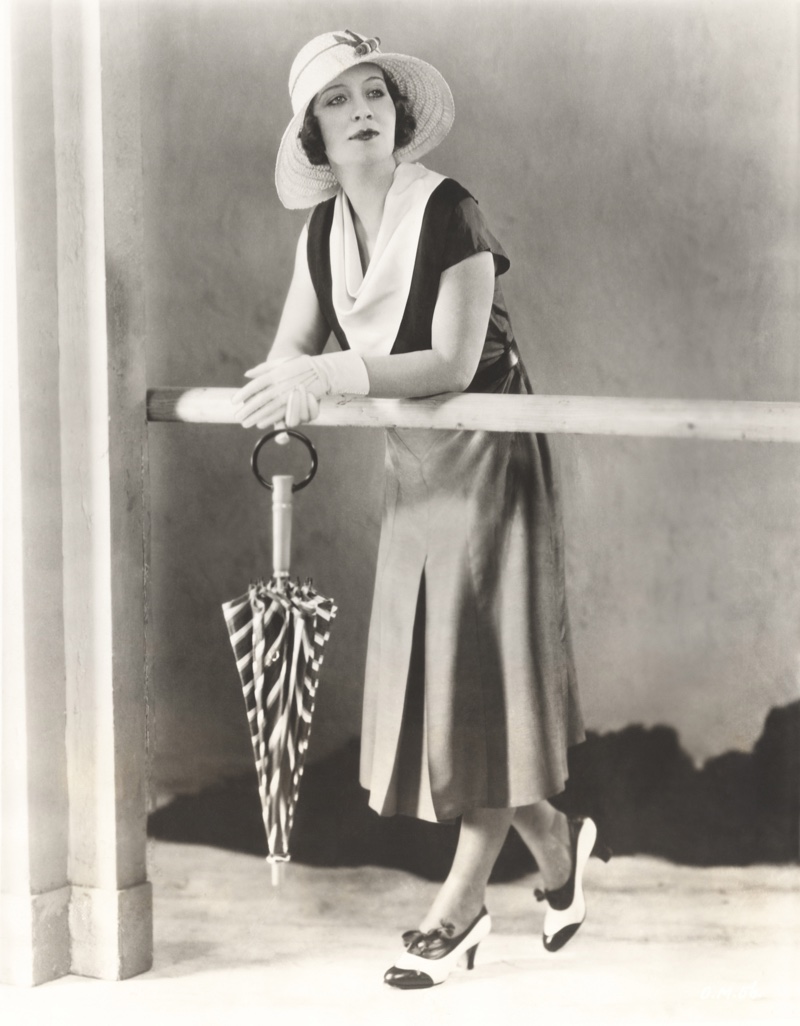 Woman poses in a daytime look including cowl neck dress, sun hat, and short gloves. Photo: Shutterstock.com