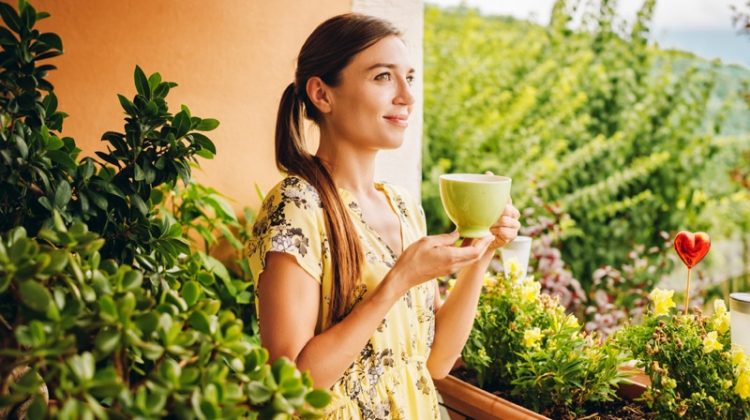 Young Woman Holding Green Tea Cup Yellow Dress Plants