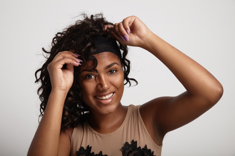 Black Woman Putting On Curly Wig