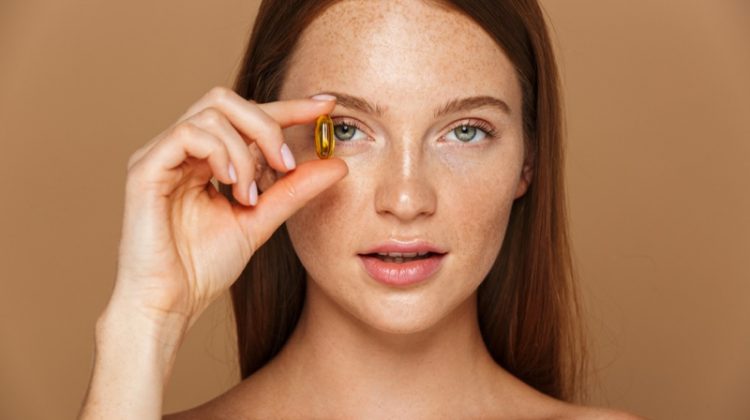 Model Freckled Face Holding Vitamin Gel
