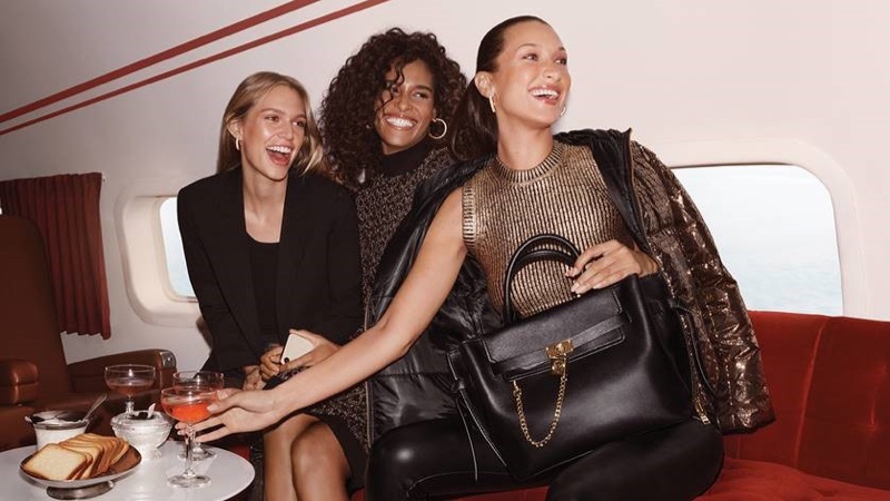 Posing on a jet, Nikki McGuire, Cindy Bruna, and Bella Hadid front MICHAEL Michael Kors Holiday 2021 campaign.