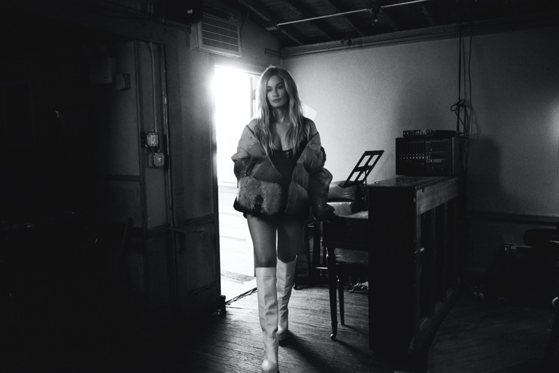 Photographed in black and white, Kacey Musgraves wears Coach jacket, boots, and bag. | Photo Credit: Courtesy of V Magazine / Blair Getz Mezibov