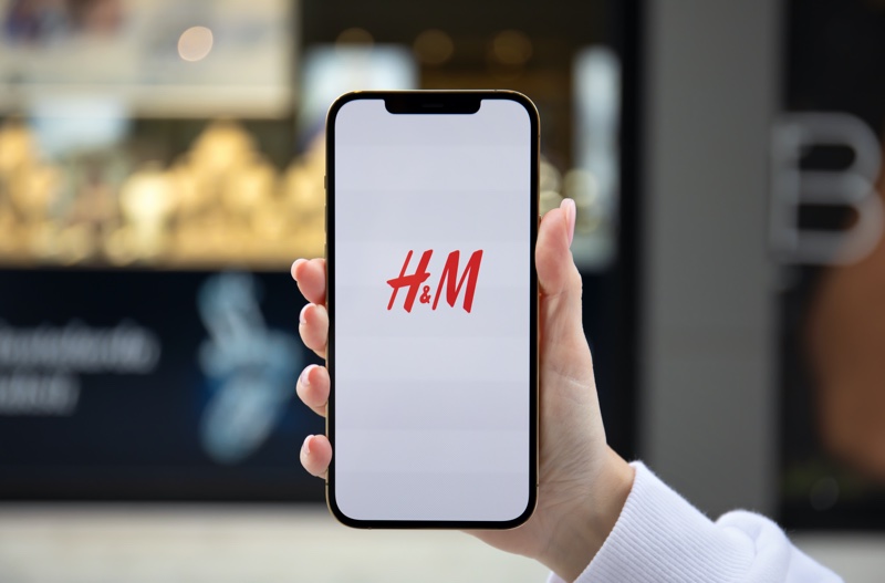 Woman Holding Phone HM Logo Screen