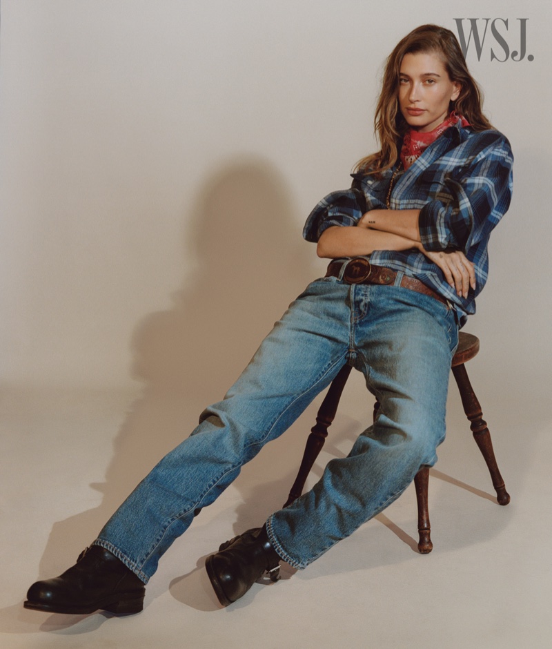 Hailey Bieber poses in plaid shirt and jeans