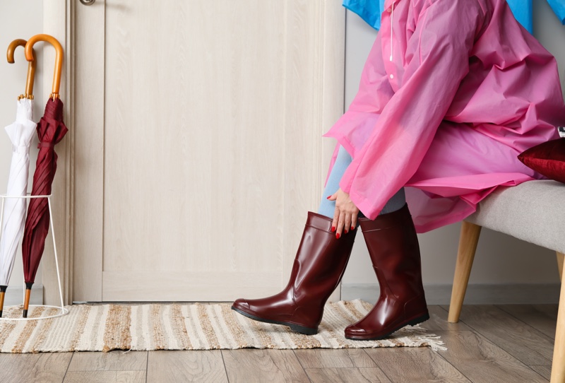Mud Room Woman Putting Burgundy Rain Boots Pink Coat