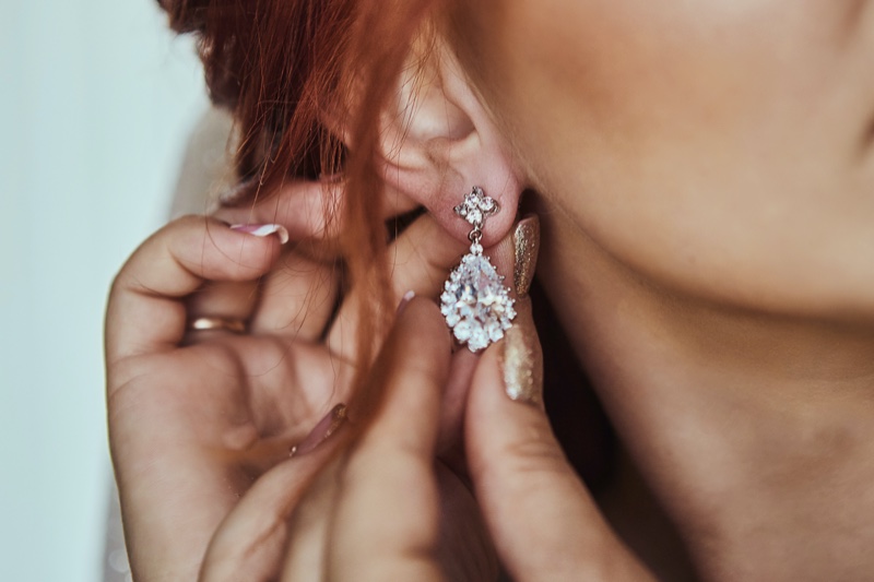 Woman Putting Diamond Earrings Closeup