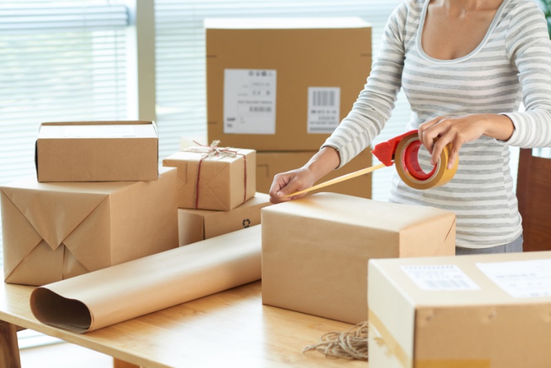 Woman Taping Boxes to Mail