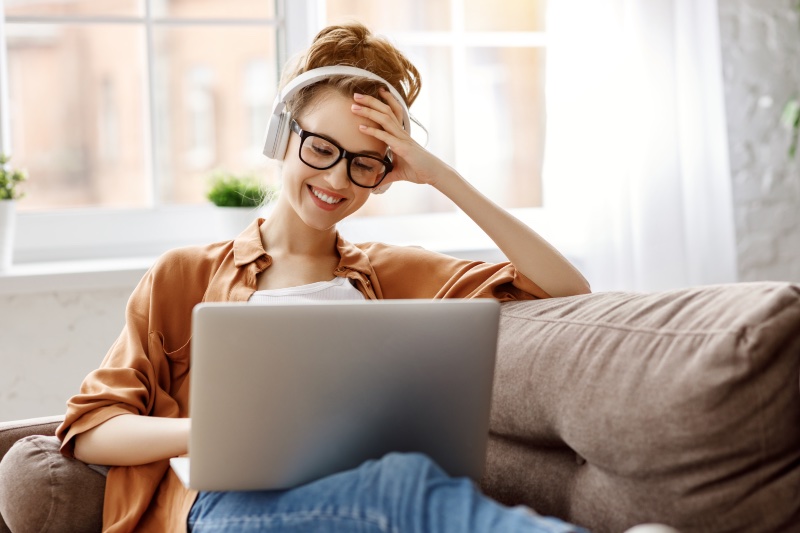 Woman Laptop Headphones Smiling Jeans Couch Home