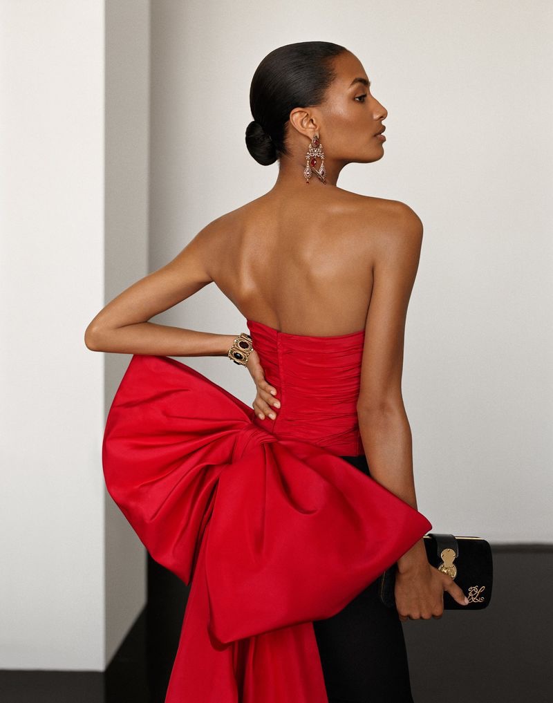Sacha Quenby poses in red dress with oversized bow for Ralph Lauren Holiday 2022 campaign.