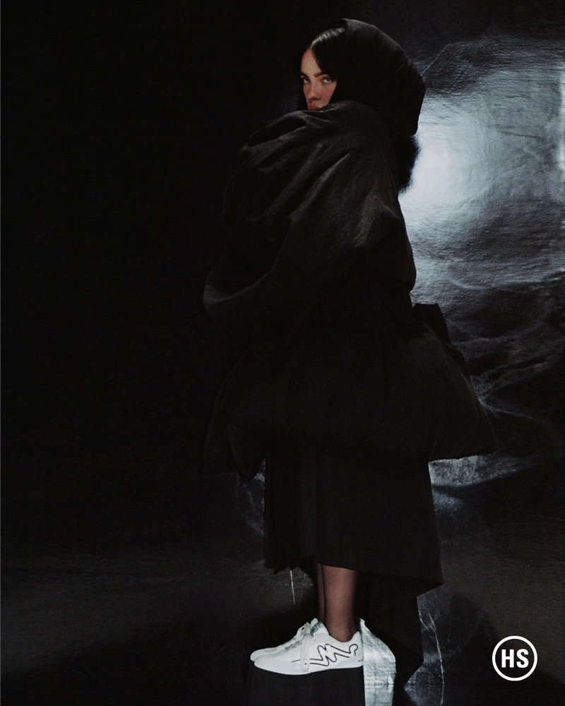 Singer Billie Eilish wears Yohji Yamamoto coat with Marc Jacobs skirt and sneakers.
