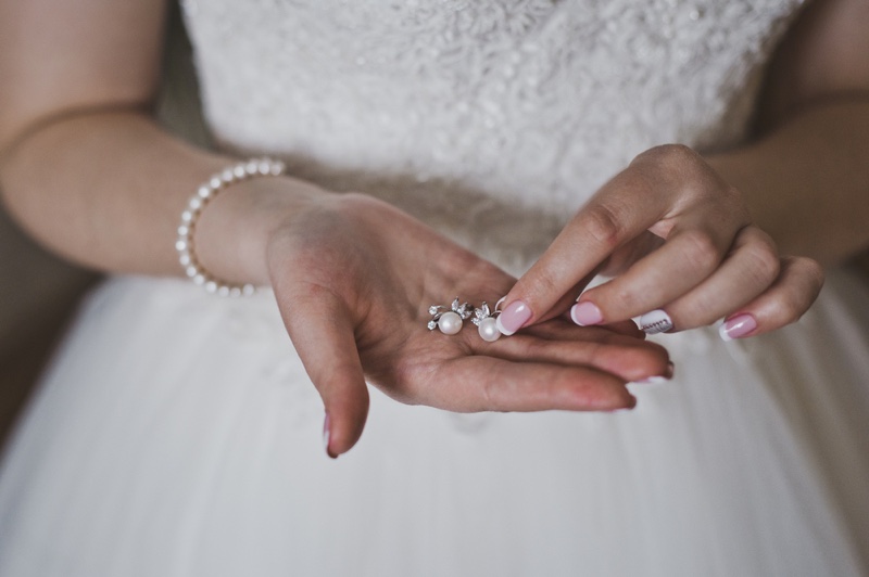 bride holding pearl earrings