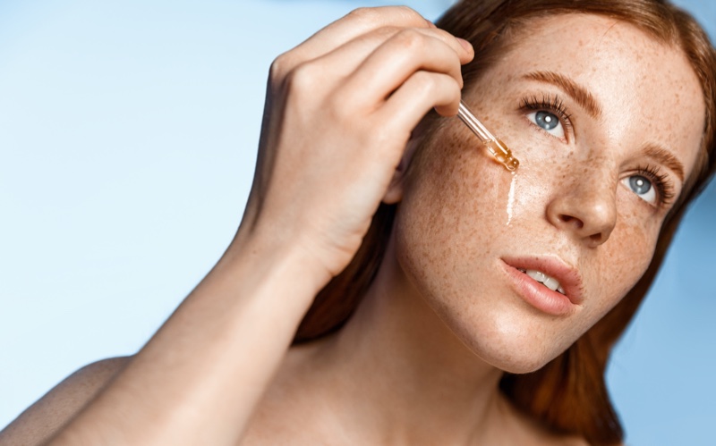 woman freckles skin applying serum