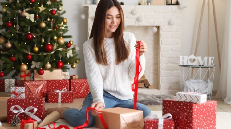 woman wrapping gifts by tree