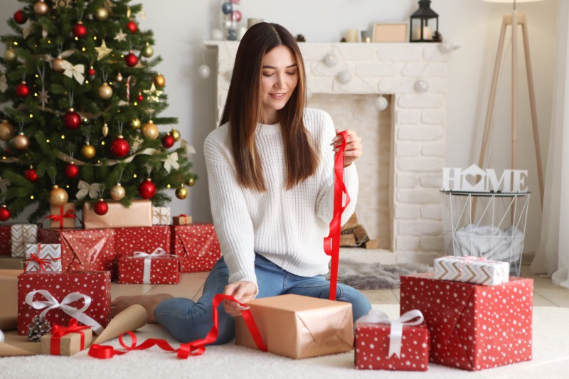 woman wrapping gifts by tree