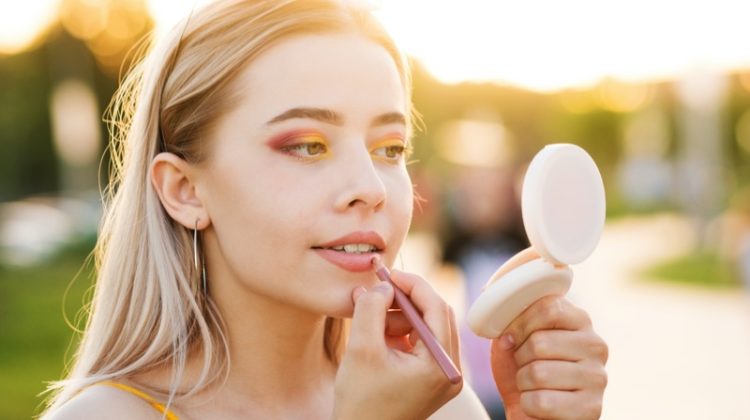 young woman applying makeup compact mirror