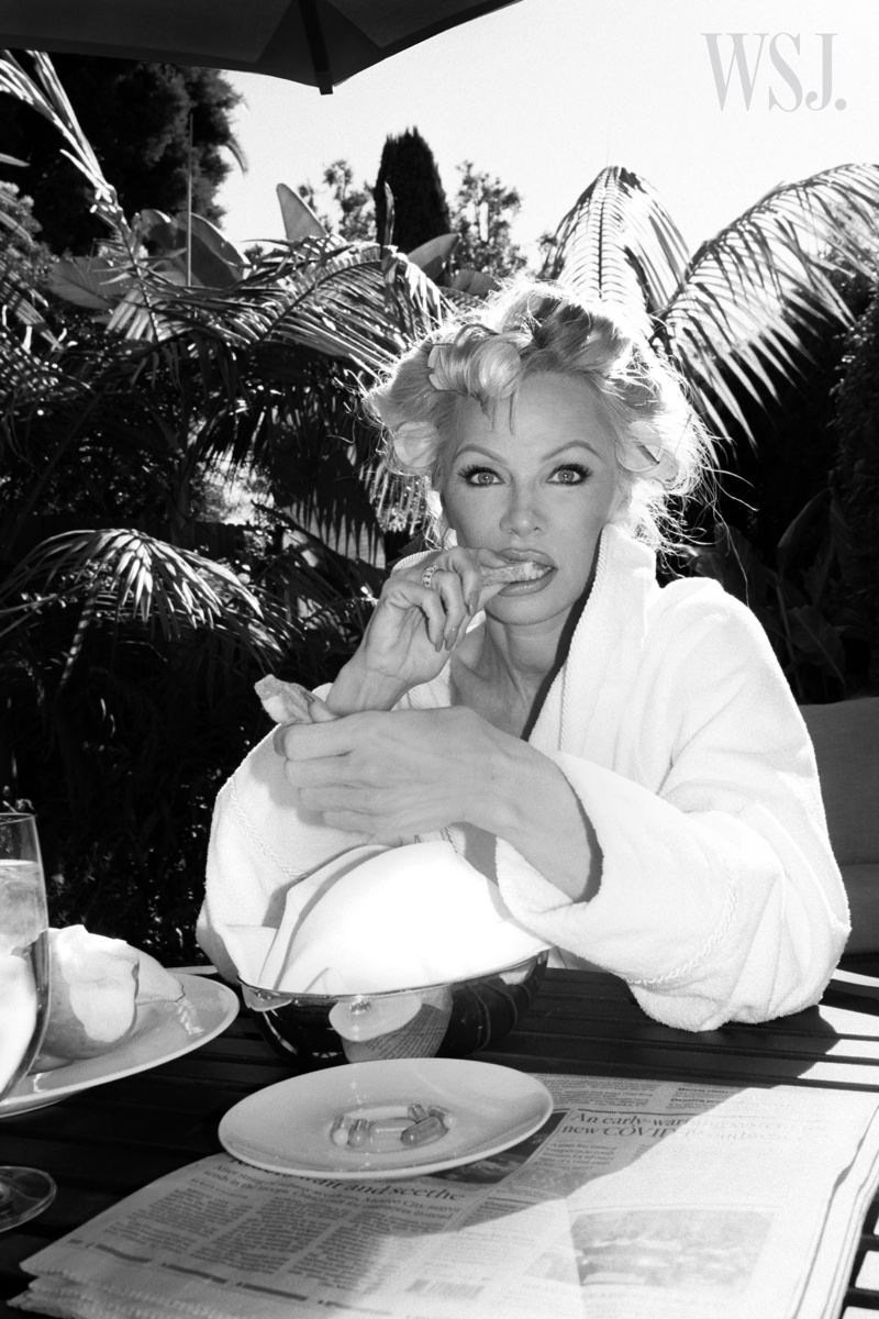 Photographed in black and white, Pamela Anderson poses in a robe.